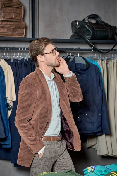 Bel homme parlant par smartphone et regardant loin tout en faisant du shopping dans la boutique — Photo de stock