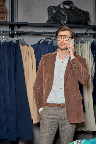 Hombre guapo hablando por teléfono inteligente mientras que las compras en boutique - foto de stock