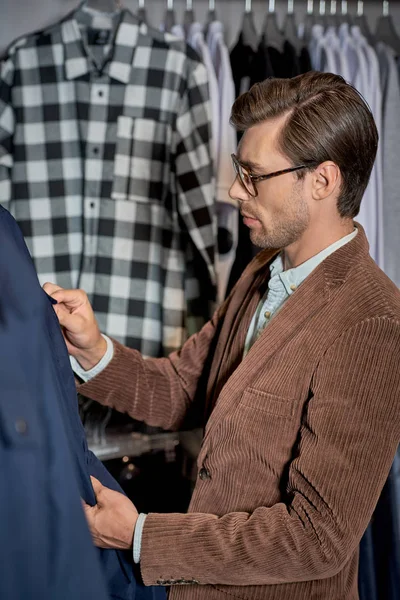 Hombre en gafas de vista la elección de la ropa mientras que las compras en boutique - foto de stock