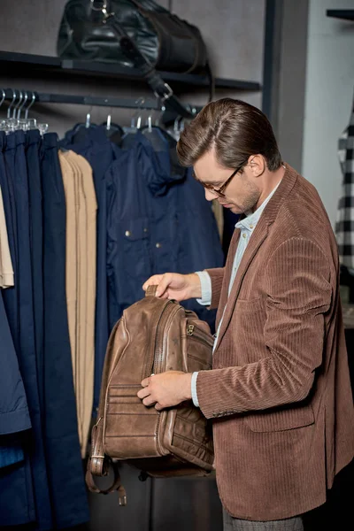 Чоловік в окулярах тримає рюкзак під час покупки в магазині — стокове фото
