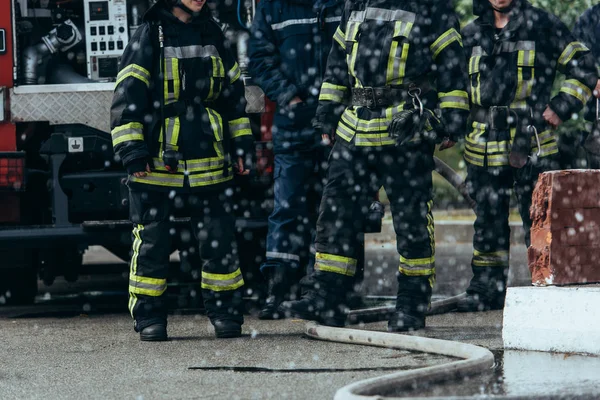 Vista parcial de la brigada de bomberos y manguera de agua en el suelo en la calle - foto de stock