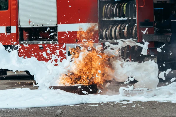 Vista ravvicinata dell'estinzione di schiuma, fiamme e camion dei pompieri sulla strada — Foto stock