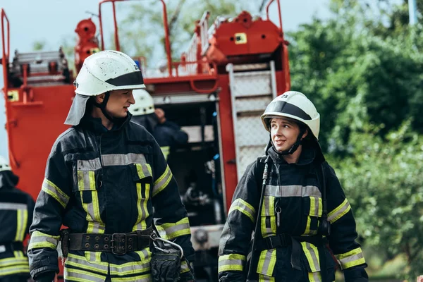 Firefighters in protective uniform looking at each other on street — Stock Photo