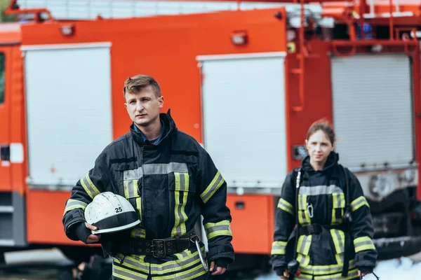 Foyer sélectif des pompiers en uniforme ignifuge dans la rue avec camion de pompiers derrière — Photo de stock