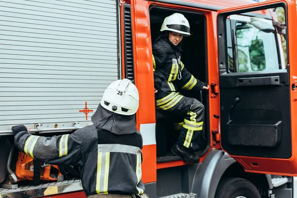 Vista parziale dei vigili del fuoco in caschi a camion dei pompieri sulla strada — Foto stock