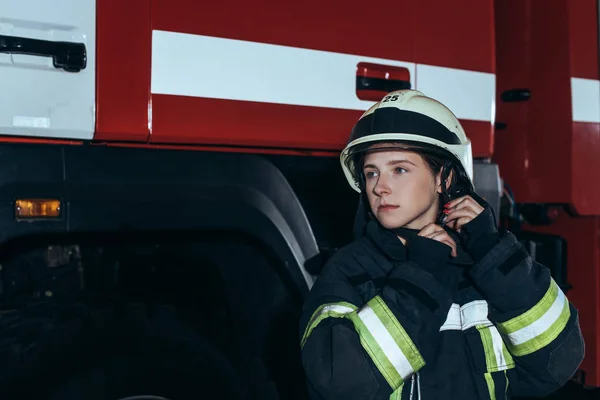 Ritratto di donna pompiere in uniforme casco di controllo alla caserma dei pompieri — Foto stock