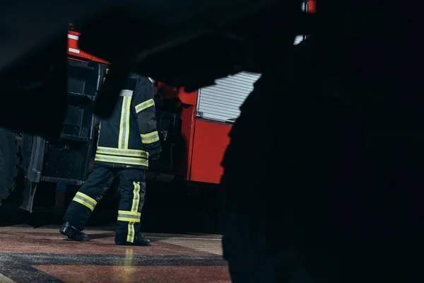 Vue partielle du pompier en uniforme ignifuge de protection marchant à la caserne de pompiers — Photo de stock