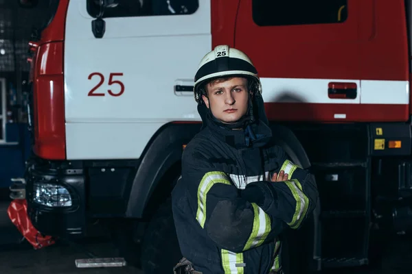 Портрет пожежника в захисній формі і шоломі з обіймами, схрещеними у пожежному відділенні — стокове фото