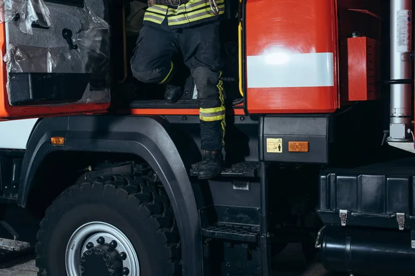 Partial view of firefighter in fireproof uniform getting out of truck at fire station — Stock Photo