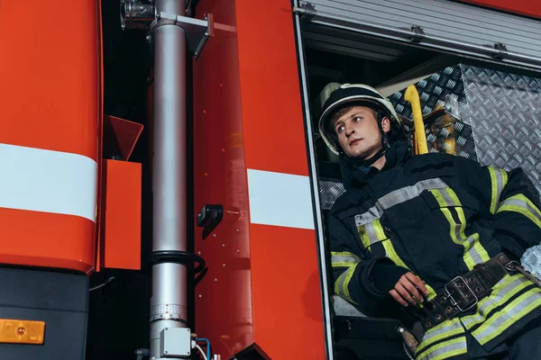 Низький кут зору пожежника в шоломі, який дивиться у відділ вогню — стокове фото