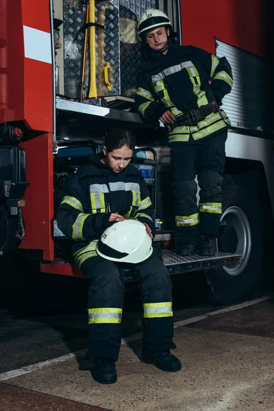 Pompiers en uniforme de protection près du camion au service d'incendie — Photo de stock