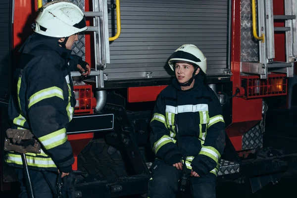 Vigili del fuoco in uniforme ignifuga e caschi che conversano alla caserma dei pompieri — Foto stock