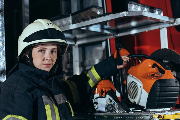 Retrato da mulher bombeira em pé no equipamento do caminhão no corpo de bombeiros — Fotografia de Stock