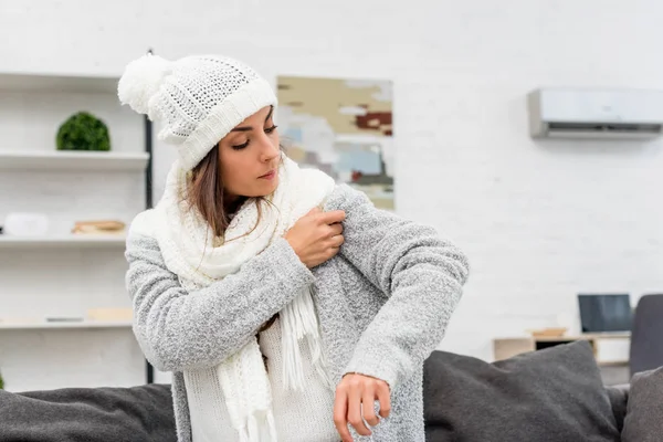 Jeune femme congelée portant des vêtements chauds avec air conditionné suspendu sur le fond — Photo de stock