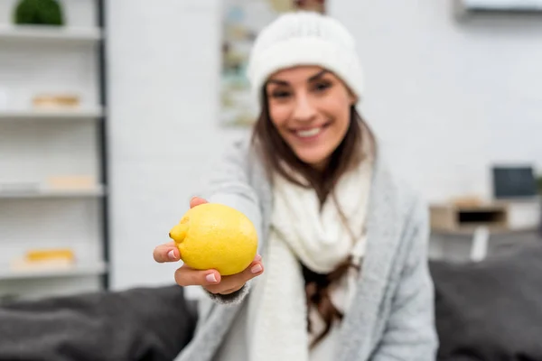 Heureuse jeune femme en vêtements chauds montrant citron à la caméra — Photo de stock