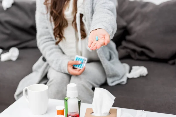 Cropped shot of sick woman in warm clothes holding pill in hand — Stock Photo