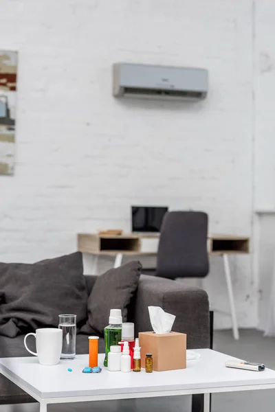 Tavolo con vari medicinali in soggiorno con posto di lavoro sullo sfondo — Foto stock