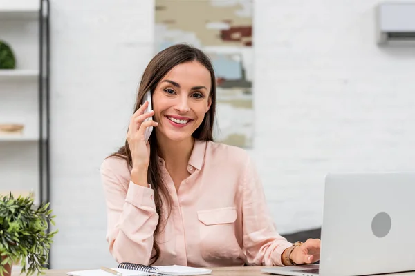 Schöne junge Geschäftsfrau telefoniert und schaut im Büro in die Kamera — Stockfoto
