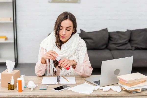 Sick young businesswoman holding cough syrup at workplace — Stock Photo