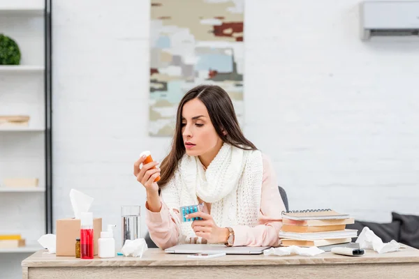 Malato giovane donna d'affari in possesso di medicinali mentre seduto sul posto di lavoro — Foto stock