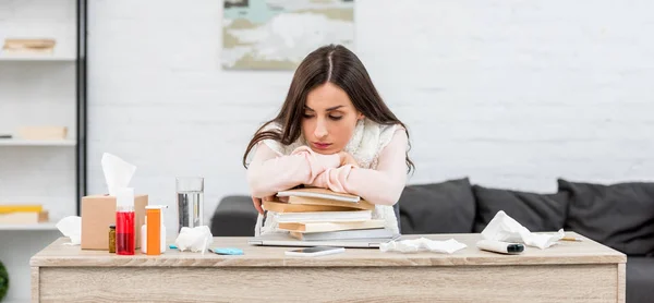 Kranke junge Frau lehnt am Arbeitsplatz an Bücherstapel — Stockfoto