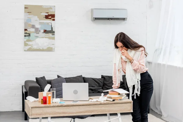 Kranke junge Frau liest und niest im Home Office — Stockfoto