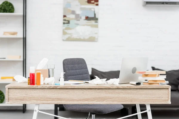 Local de trabalho de escritório bagunçado com laptop e vários medicamentos — Fotografia de Stock