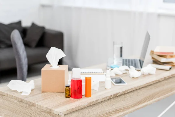 Close-up shot of messy office workplace with laptop and various medicines and paper napkins — Stock Photo