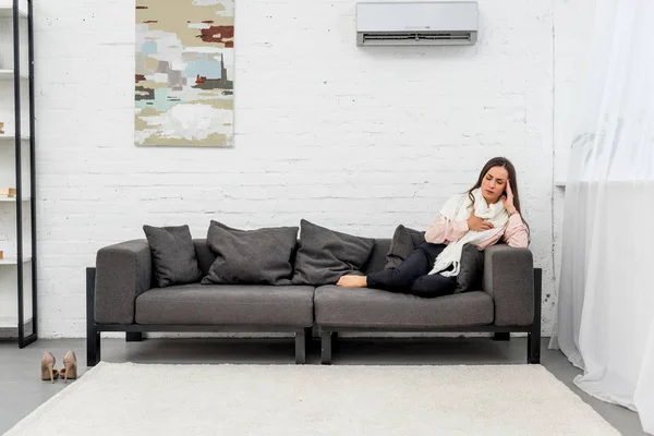 Malato giovane donna sdraiata sul divano sotto aria condizionata a casa — Foto stock
