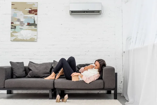 Vue latérale de la jeune femme malade couchée sur le canapé à la maison — Photo de stock