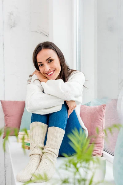 Attrayant jeune femme se détendre sur le rebord de la fenêtre avec des coussins à la maison — Photo de stock