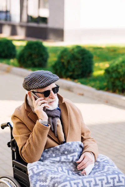 Anziano disabile in sedia a rotelle che parla per telefono per strada — Foto stock