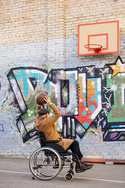 Senior disabile uomo in sedia a rotelle giocare a basket in strada — Foto stock