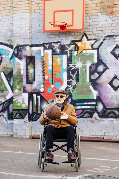 Active senior disabled man in wheelchair with basketball ball on street — Stock Photo