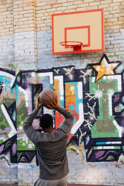 Schöner afrikanisch-amerikanischer Mann wirft Basketballball in Ring auf der Straße — Stockfoto