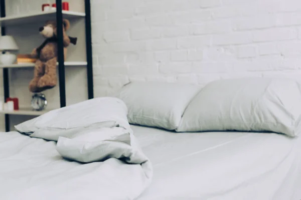 Vista de cerca de la cama con manta y almohadas durante la mañana en casa - foto de stock