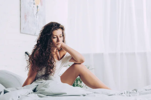Pretty curly girl posing in bed during morning time at home — Stock Photo