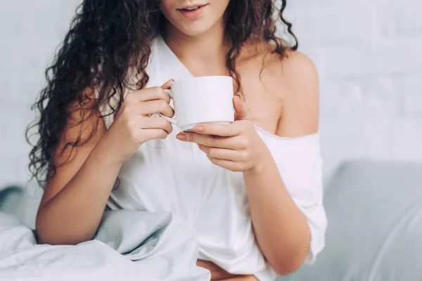 Partial view of woman drinking coffee in bed during morning time at home — Stock Photo