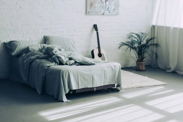 Interior of modern bedroom with guitar and houseplant — Stock Photo