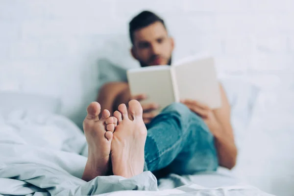Selektiver Fokus des Mannes, der zu Hause im Schlafzimmer Buch liest — Stockfoto