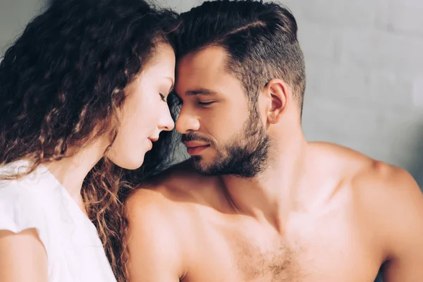 Vista lateral de pareja joven con los ojos cerrados sentado cara a cara - foto de stock