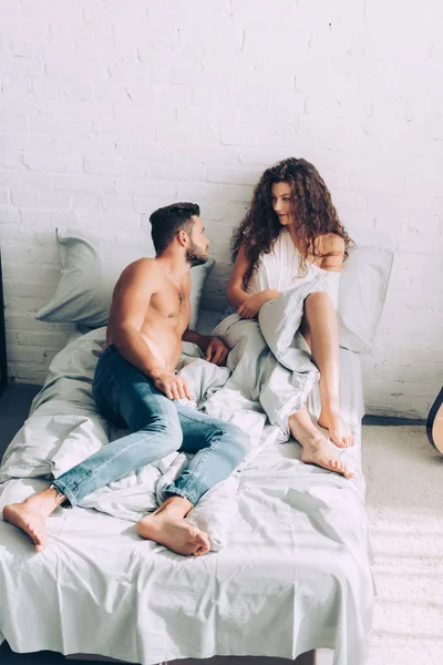 Vista de ángulo alto de la joven pareja sentada en la cama por la mañana en casa - foto de stock