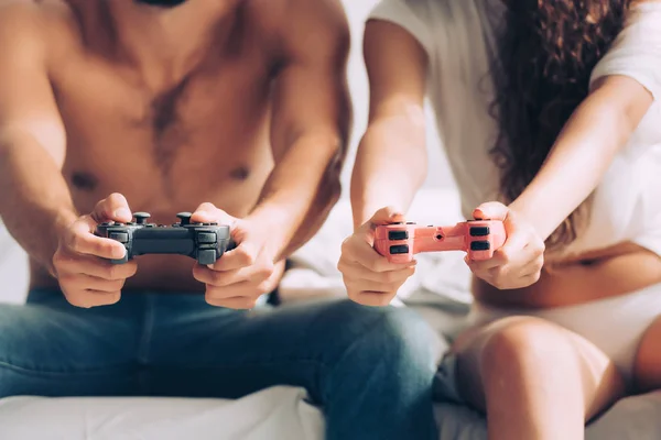 Image recadrée de couple jouant jeu vidéo par joysticks à la maison — Photo de stock