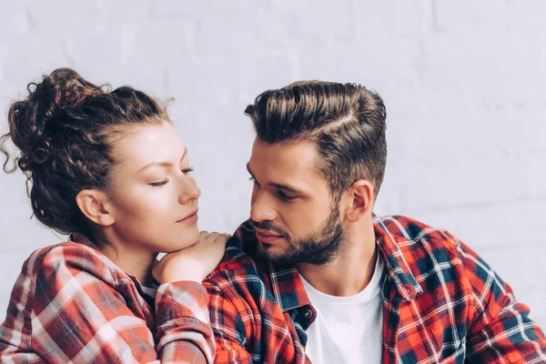 Pretty young woman in checkered shirt embracing boyfriend at home — Stock Photo