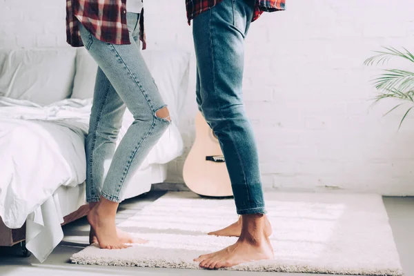 Partial view of couple in jeans standing next to each other in bedroom at home — Stock Photo