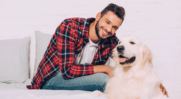 Jovem feliz petting adorável golden retriever no quarto em casa — Fotografia de Stock