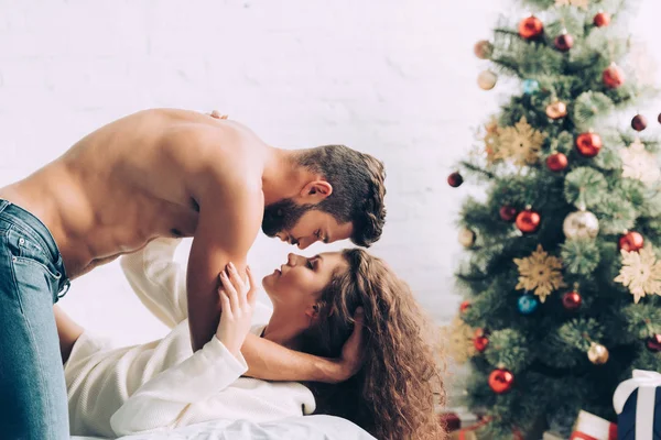 Shirtless handsome man laying on beautiful curly girlfriend in bedroom at home — Stock Photo