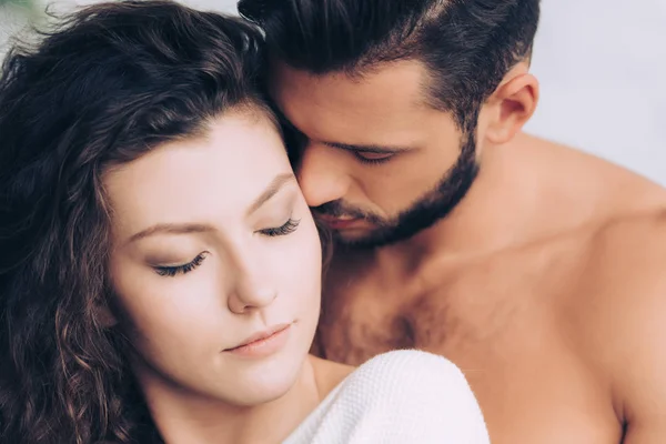 Handsome man kissing beautiful curly girlfriend posing with closed eyes — Stock Photo