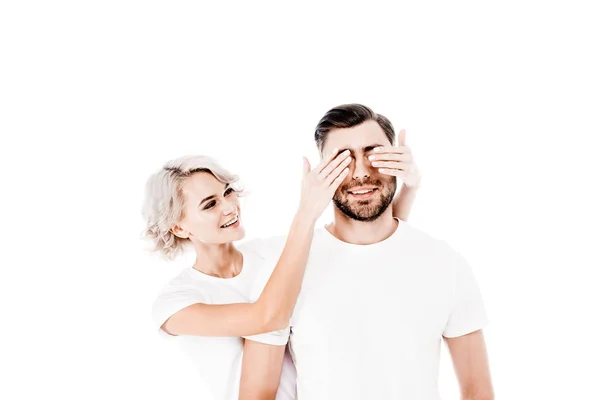 Felice donna sorridente chiudendo gli occhi del suo fidanzato isolato su bianco — Foto stock