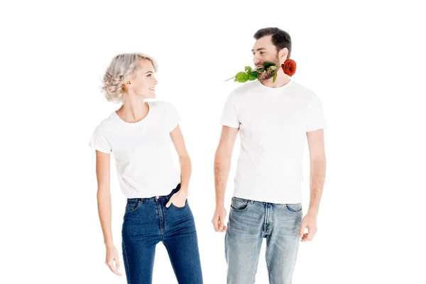 Hermosa pareja mirándose mientras el hombre sostiene la flor en la boca aislada en blanco - foto de stock